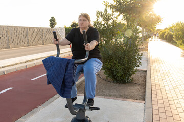 Plus size woman exercising on outdoor elliptical machine