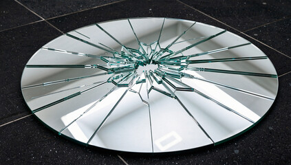 Broken Oval Mirror with Sharp Fractures on Dark Surface