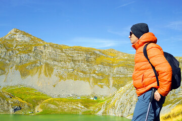 A solo tourist enjoys the view of the mountains near Kapetanovo Lake on an autumn day. Symbolizes reflection moment, digital detox concept, emotional balance outdoors, and mindfulness travel narrative