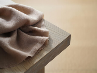 Quiet luxury still life Cashmere scarf on oak surface soft folds neutral palette texture focus serene