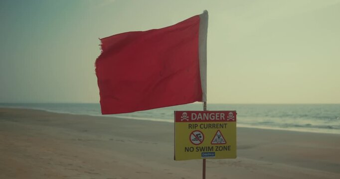 Red flag on beach warning of rip currents, creating a tense atmosphere