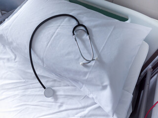 Stethoscope lying on a white pillow in an empty hospital room