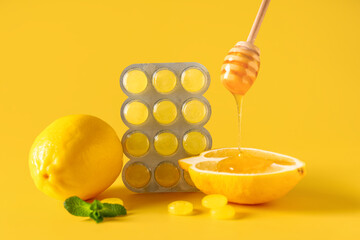Cough drops in blister with lemon, mint leaves, dipper and honey on yellow background