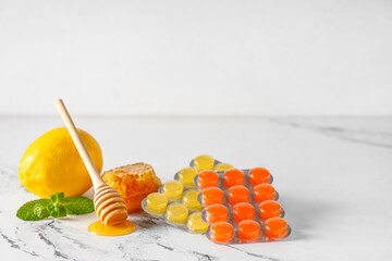 Cough drops in blisters with lemon, mint leaves and honeycomb on light background