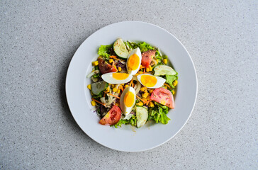 Top view of egg salad on the white plate. cruttong. mix salad. boiled egg. dressing. vegetables. high angle, above, flat lay. close up. granite table on the background. isolated. grey or gray. 