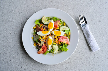 Top view of egg salad on the white plate. cruttong. mix salad. boiled egg. dressing. vegetables. high angle, above, flat lay. close up. granite table on the background. isolated. spoon, fork, tissue.
