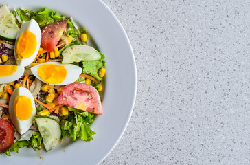 Top view of egg salad on the white plate. cruttong. mix salad. boiled egg. dressing. vegetables. high angle, above, flat lay. close up. granite table on the background. isolated. half. copy space