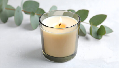 Close-up of a softly burning candle in a transparent holder surrounded by eucalyptus leaves, ideal for spa, aromatherapy, mindfulness, and soothing natural aesthetics.