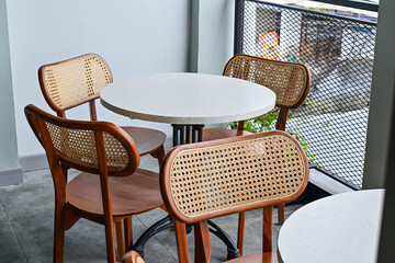 Empty tables And wooden chairs, grey or gray, granite. set. outdoor seating for restaurant, Cafe or coffee shop. Plants, leaves, green, nature, wall. wood. brown. white. wall. black iron fence. decor,