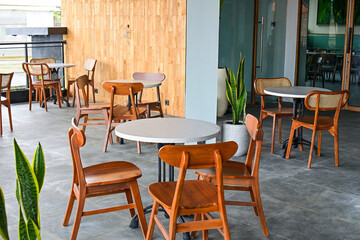 Empty tables And wooden chairs, grey or gray tables and chairs set. outdoor seating for restaurant, Cafe or coffee shop. Plants, leaves, green, nature, wall. wood. granite. brown. white. wall. decor, 