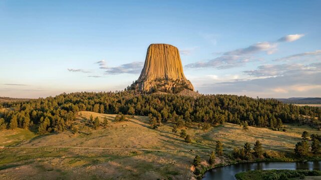 Majestic Devils Tower National Monument Wyoming USA at Sunset Golden Hour Warm Light Illuminating Rock Formation Surrounded by Pine Forest