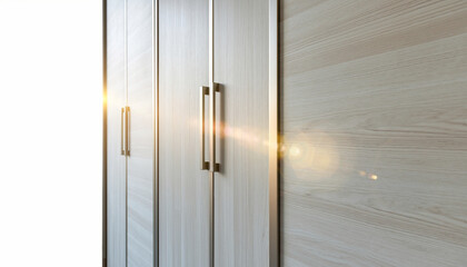 Modern light-colored wooden wardrobe or closet doors with elegant metal handles, featuring a bright lens flare creating a warm, inviting atmosphere in a contemporary interior setting.