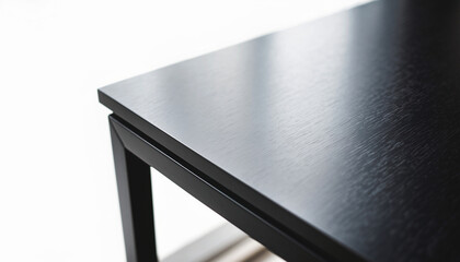 Close-up detail of a modern black wooden table surface with subtle grain texture, featuring clean lines and a minimalist design, isolated on a bright white background for copy space.