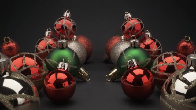 A collection of Christmas ornaments in red, green, and silver, arranged on a dark background with reflective surfaces.