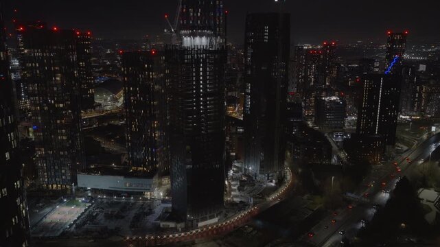 Establishing aerial view of Manchester at night. Illuminated skyline of city in the north of England, United Kingdom