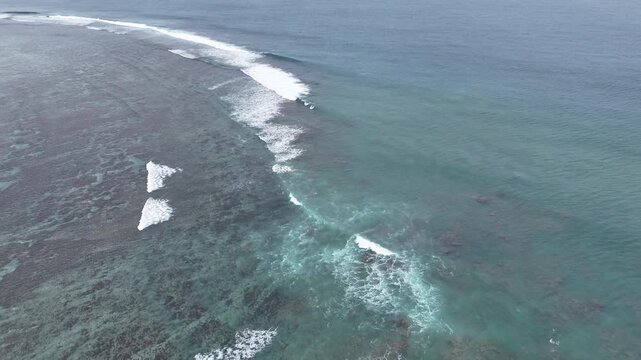 Aerial drone view of a coral reef and crashing waves in the South Pacific, Tonga. Stunning turquoise waters and white surf captured from above in a remote tropical island paradise