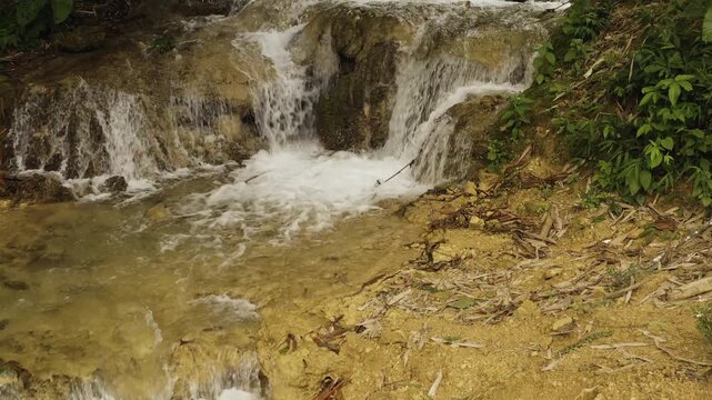 Cinematic footage showcasing the multi-tiered Thac Hieu waterfall cascading through dense tropical forest and terraced rice fields in Pu Luong Nature Reserve.