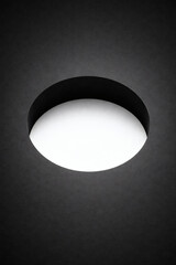 Abstract minimalist image featuring a bright white circle set against a dark background, creating a striking contrast. Simple yet captivating art.