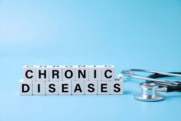 White blocks spelling 'CHRONIC DISEASES' next to a stethoscope on a blue background. Copy space