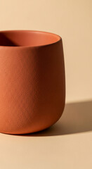 A terracotta-colored ceramic mug mockup, rich warm earth-tone finish, minimalist studio background in light beige