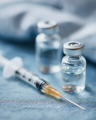 A syringe sits beside vials filled with liquid, arranged on a sterile surface Generative AI