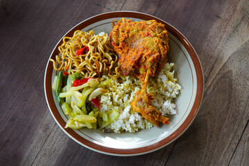 Bebek rica spicy duck dish with rich chili seasoning, served with steamed rice, stir-fried noodles, and vegetables, bold Indonesian flavor with rustic homestyle presentation