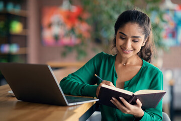Beautiful unemployed indian lady looking for job online, sitting alone at cafe, using laptop,...