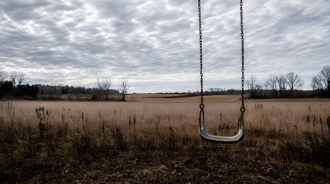 ppa. Empty playground swing moving in abandoned village under overcast sky. lifestyle magazines, social media lookbooks, designed for influencer and brand collaborations.