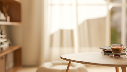 Book and coffee on wooden table and stool across window with sunlight through curtain in living room © bongkarn