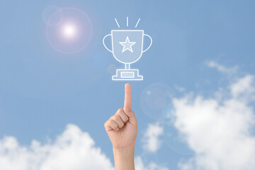 青空へ向けてトロフィーを指差しする子供の手