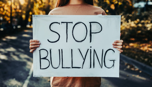 Young Person Holds Stop Bullying Sign in Park.
