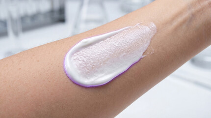 Close up of white cream swatch on human arm in laboratory. Cosmetic skincare product testing concept with blurred lab equipment background