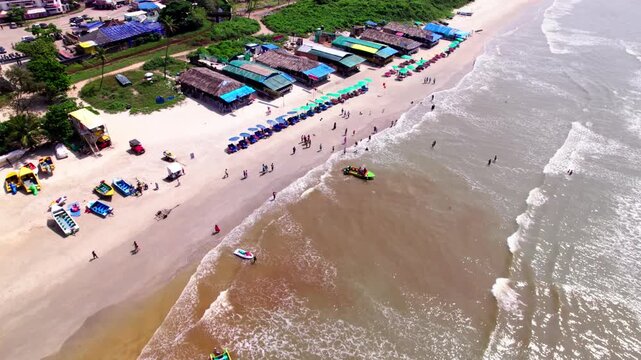 Colva Beach shoreline with Shacks, Boats, Waves and tourists at goa. day time, push back shot, drone shot, 4k.