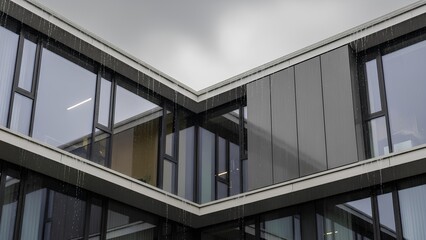 Modern building with large glass windows reflecting the overcast sky and surrounding structures.