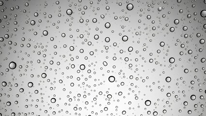 Close-up view of clear water droplets of various sizes on a transparent surface, creating a textured background.