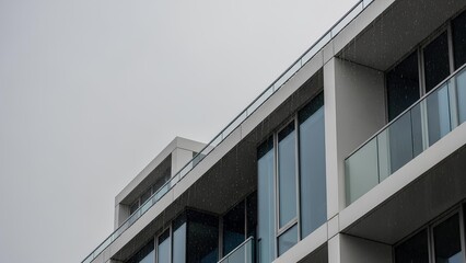 Modern architectural details of a contemporary building with balconies and large windows under an overcast sky.