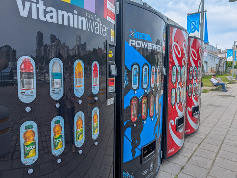 Canada, Quebec, 05 July 2025 : Vending machines with drinks beside sidewalk reflecting urban cityscape background