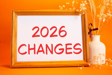 2026 Changes symbol. Concept words 2026 Changes on beautiful wooden picture frame. Beautiful orange background with flower vase. Business and 2026 Changes concept. Copy space.