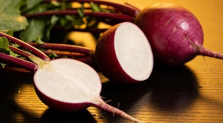 Whole and cut fresh turnips on black table