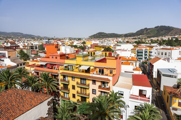 Colorful cityscape with palm trees and mountains, view over La Laguna rooftops from church bell tower in San Cristobal de La Laguna, Tenerife.