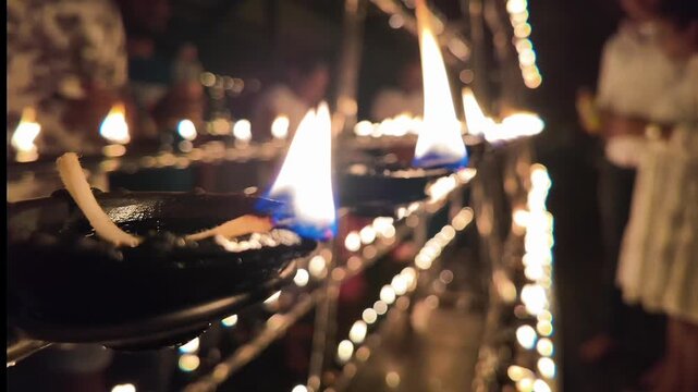 Wide view of a Sri Lankan temple courtyard illuminated by thousands of oil lamps during a Full Moon Poya day festival, showcasing vibrant local culture.