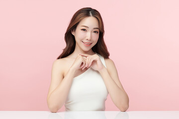 Obraz premium A beautiful young Asian woman with clean, fresh skin against a pink background. Skincare, facial treatment, cosmetology, beauty, and spa. An elegant portrait of an Asian woman.