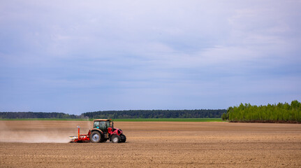 Farmer in tractor preparing farmland with seedbed for the next year. Powerful tractor at work, turning over soul on a vast farmland under a clear sky. © NastyaPhoto