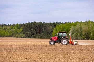 Obraz premium A farmer is seen driving a tractor, sowing seeds and planting crops in the agricultural fields during spring.