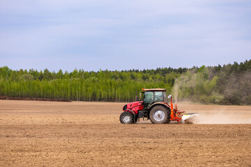 Obraz premium A farmer is seen driving a tractor, sowing seeds and planting crops in the agricultural fields during spring.