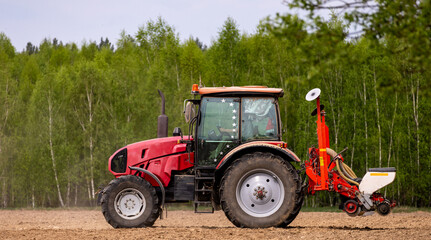 Naklejka premium Tractor drilling seeding crops at farm field. Agricultural activity. Tractor spraying pesticides at soy bean fields.