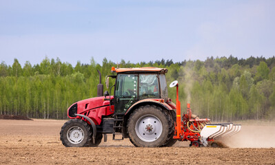 Tractor drilling seeding crops at farm field. Agricultural activity. Tractor spraying pesticides at soy bean fields.