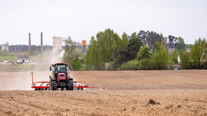 Fototapeta premium The tractor is used to sow seeds in the field using a specialized device. The tractor is a powerful tool for agricultural work, equipped with seed planters to prepare the soil for planting.