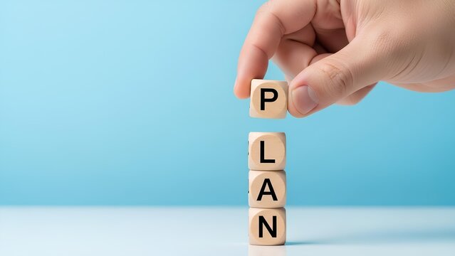 Hand stacking wooden blocks spelling out the word PLAN, symbolizing planning and strategy