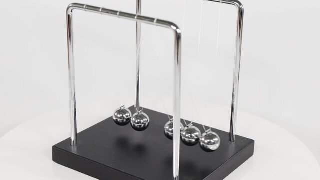 Newton's Cradle Kinetic Desk Toy Swinging on White Background